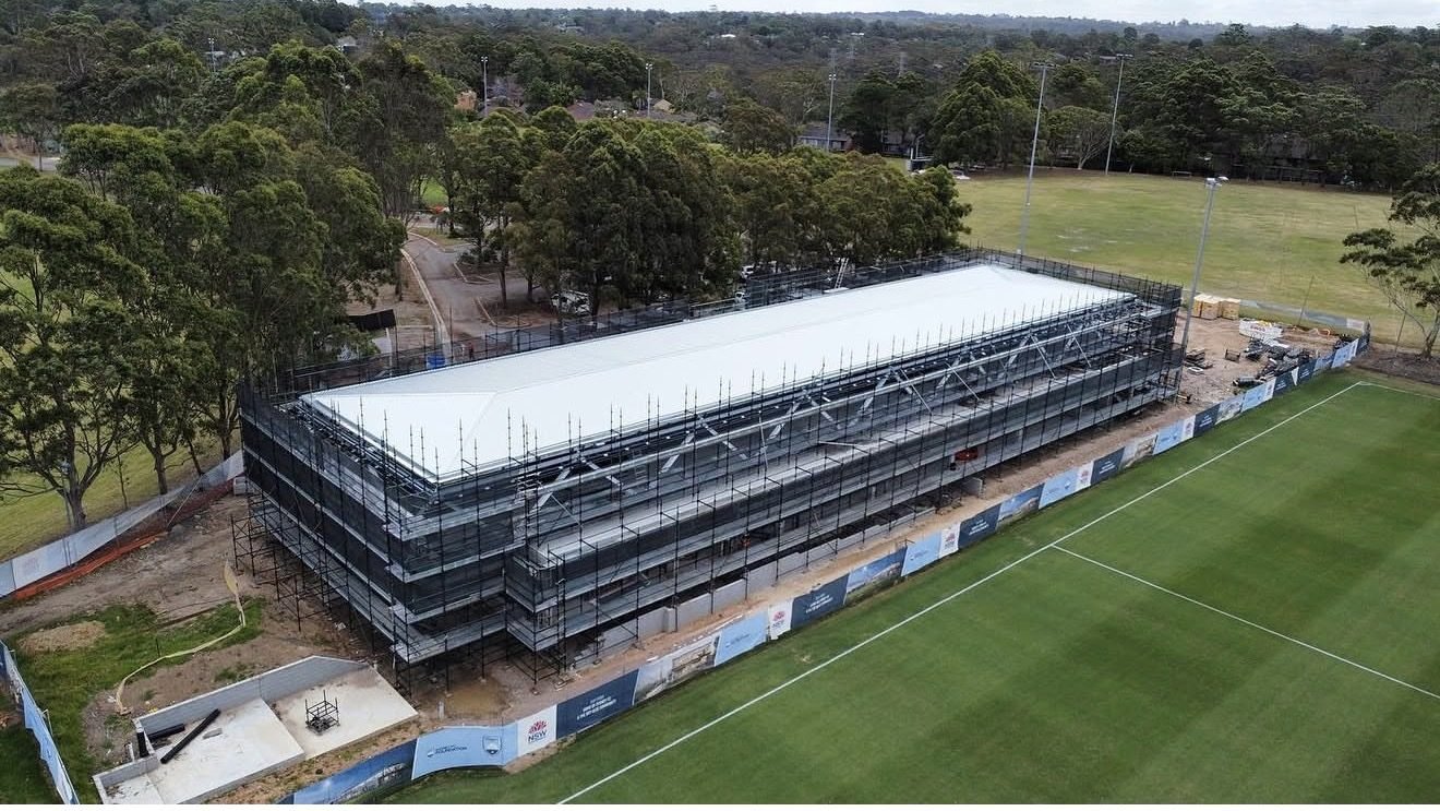 Aerial view of the pavilion with a new white metal roof beside a football field