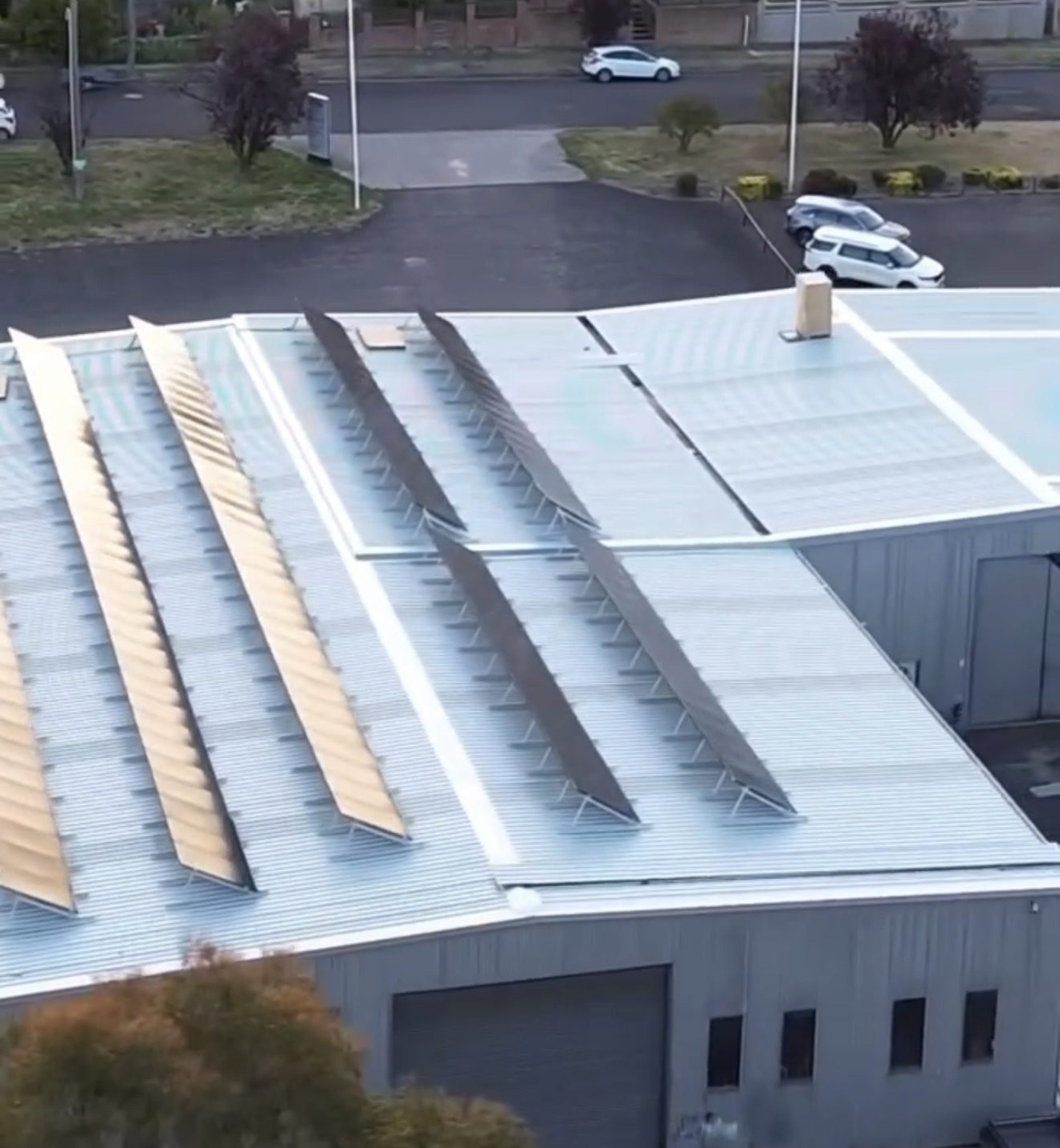 Aerial view of a warehouse roof with long rows of solar panels